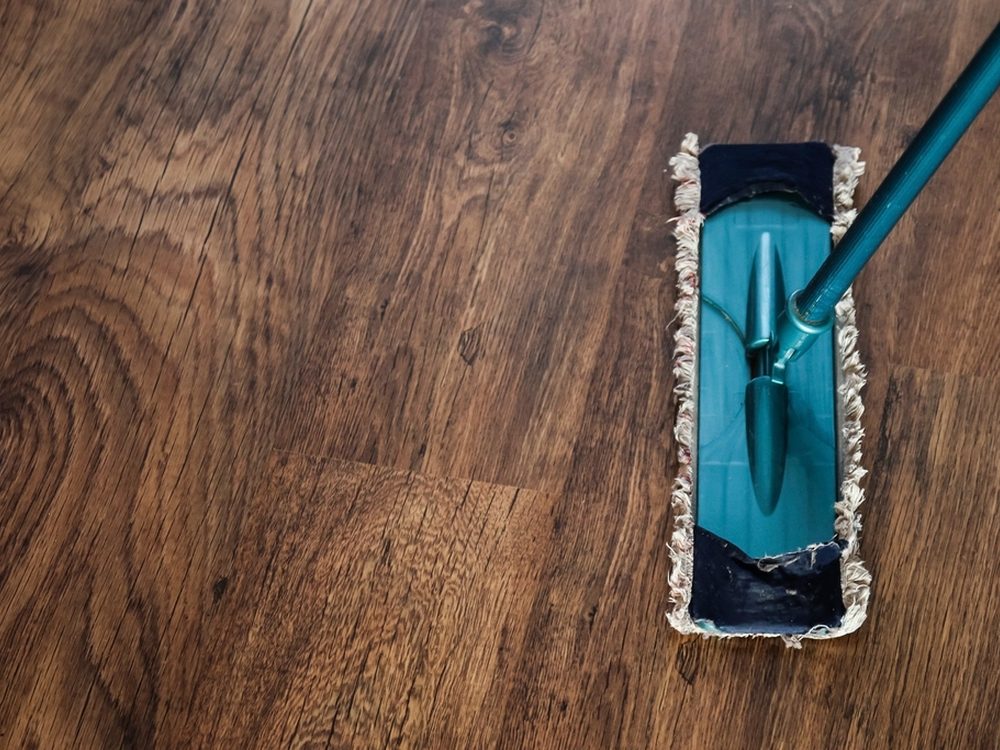 A flat mop resting on polished timber floorboards