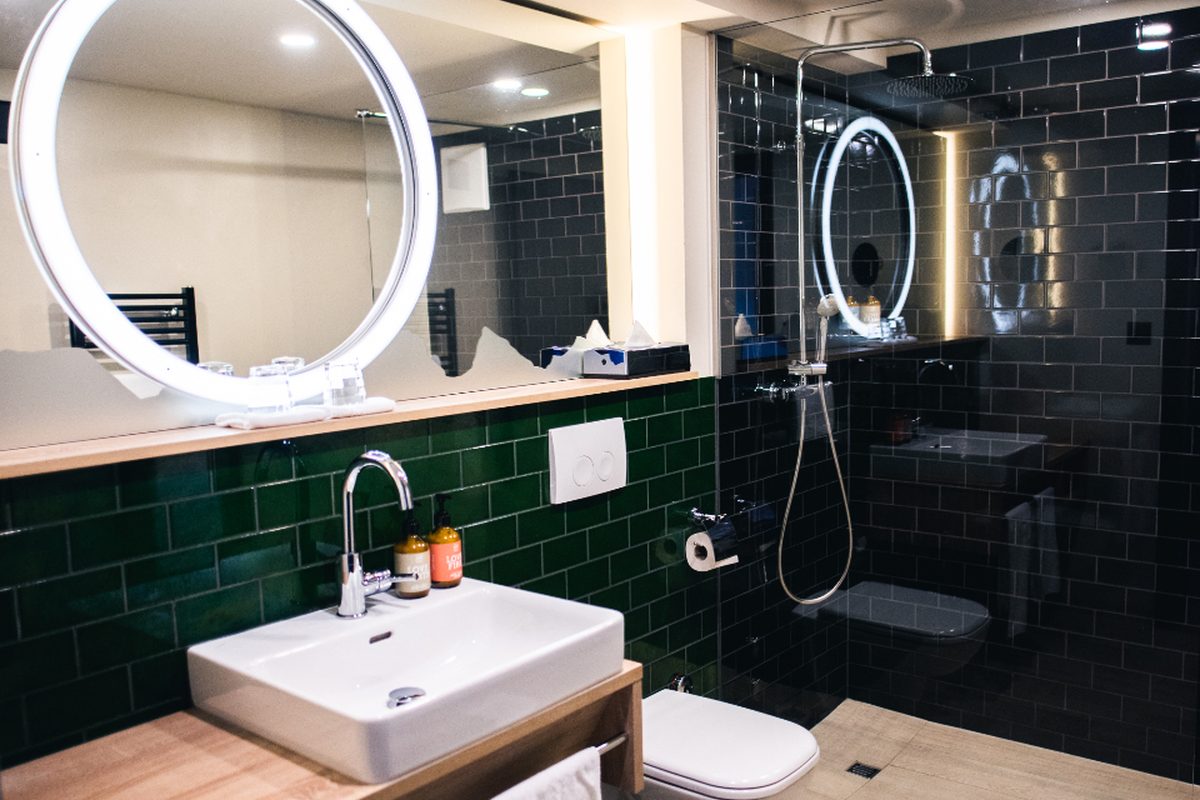 A modern bathroom with a lit round mirror