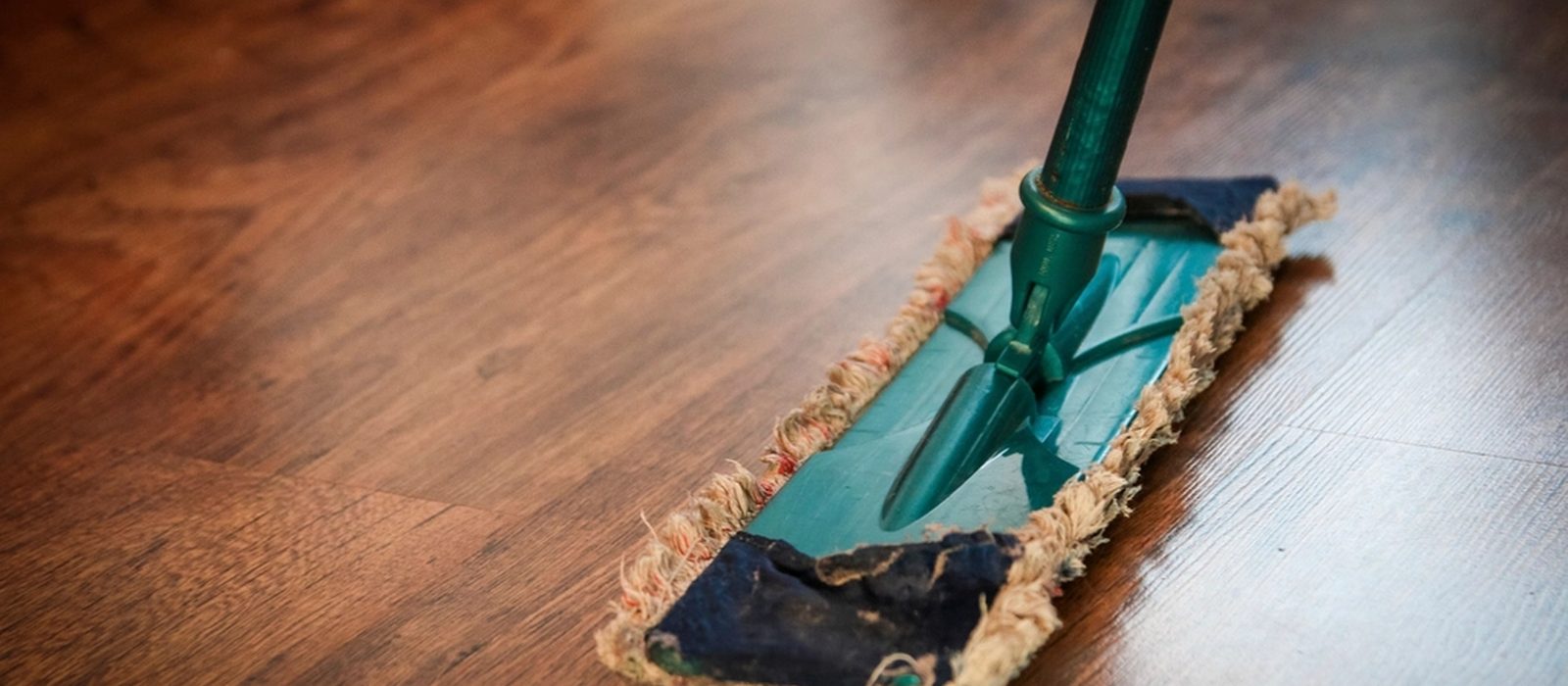 A flat mop being pushed across a timber floor