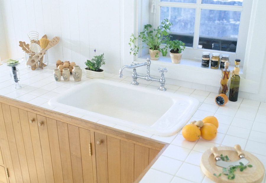 A kitchen sink and benchtop with a window above it