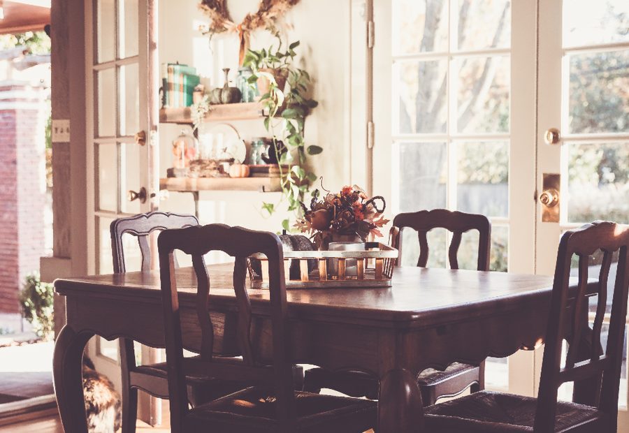 A dining room with a table set beside tall windows